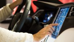 A person sitting in a car and operating the navigation system via the touch display.