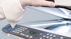 A woman operates a printer. 