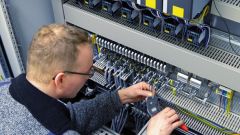 A man is working on a control cabinet.