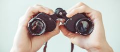 This image shows male hands holding binoculars.